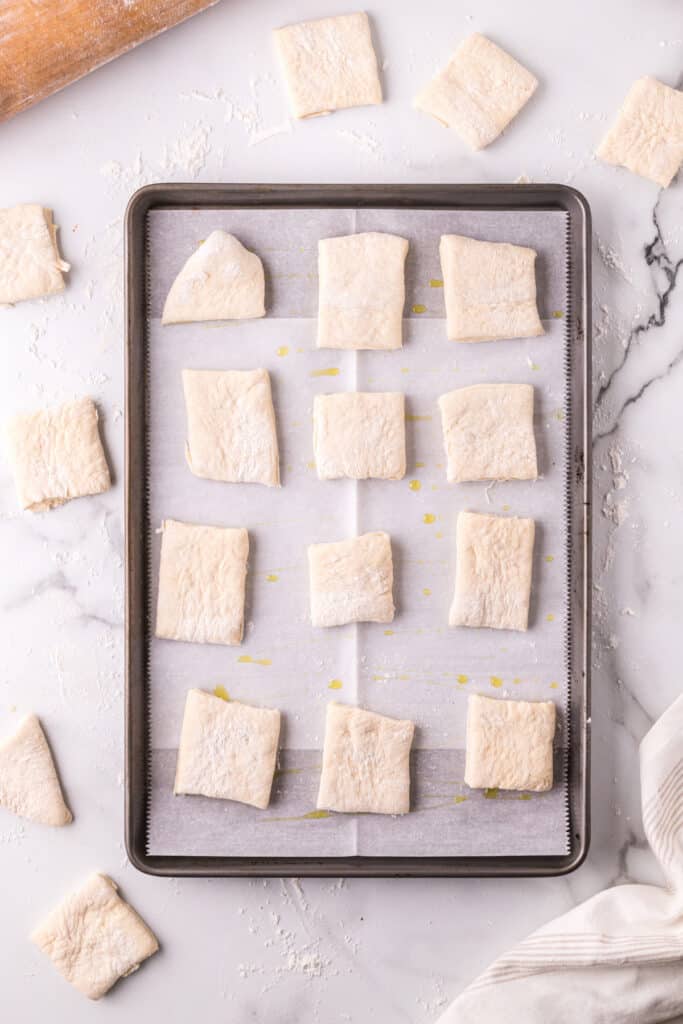 Unbaked Texas Roadhouse rolls arranged on a parchment-lined baking sheet