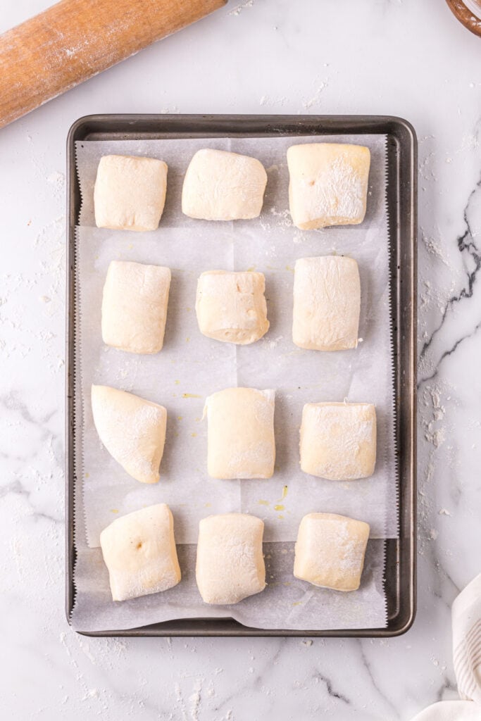 Risen Texas Roadhouse rolls on a parchment-lined baking sheet before baking