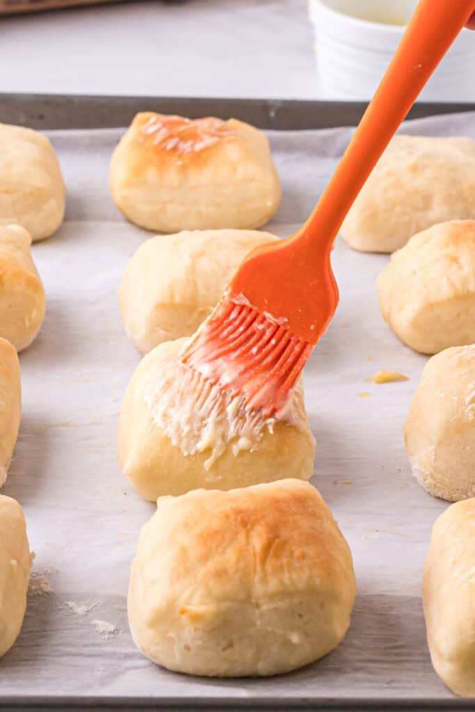 Warm Texas Roadhouse rolls being brushed with melted butter