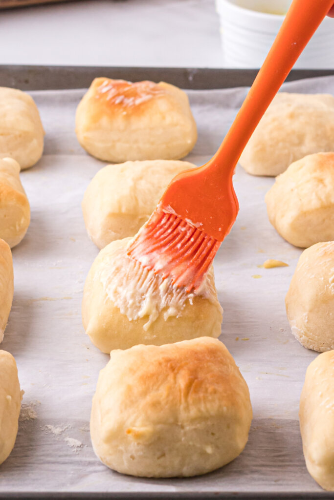 baked roll being brushed with butter