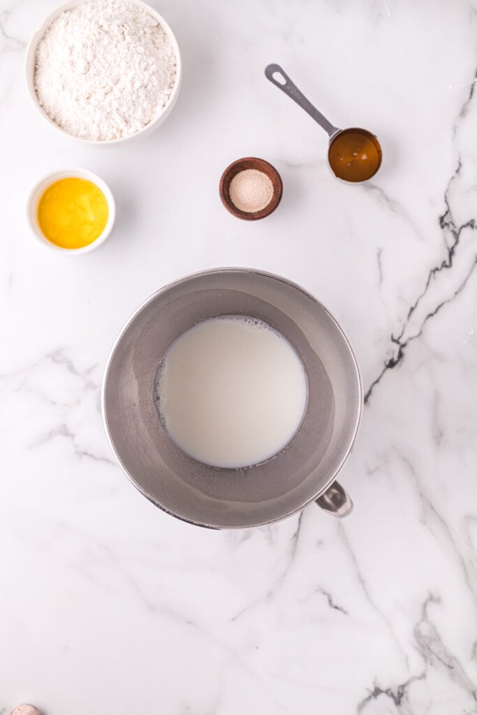 Warm milk in a mixing bowl with ingredients ready for Texas Roadhouse roll dough
