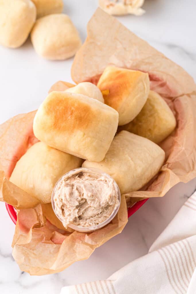 Basket of homemade Texas Roadhouse rolls served with cinnamon honey butter