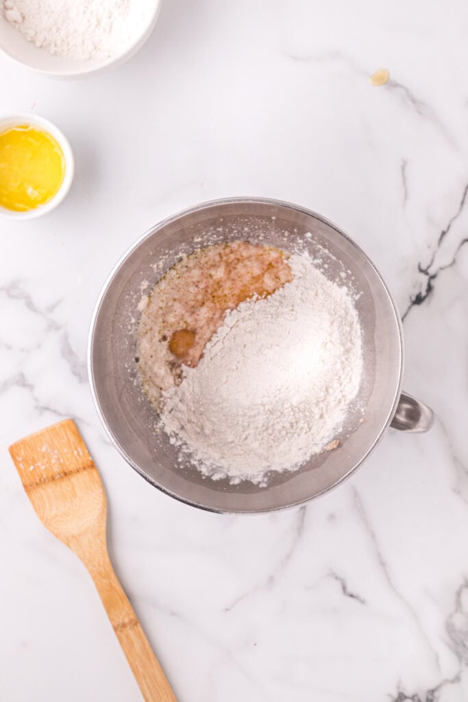 Flour added to wet ingredients in a mixing bowl for Texas Roadhouse roll dough