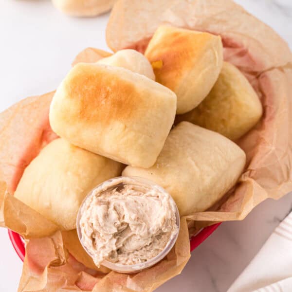 Homemade Texas Roadhouse rolls served in a basket with cinnamon honey butter