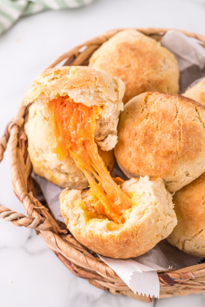 cheese biscuits in basket with top one open to show the melted cheese inside