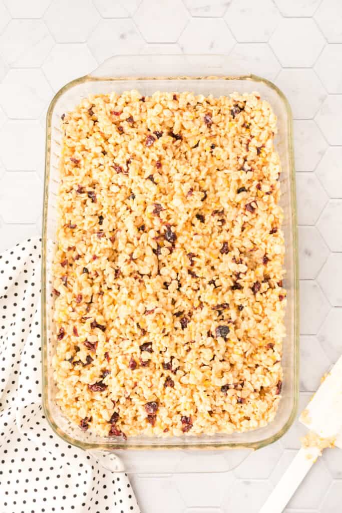 Cranberry orange crispy treat mixture pressed evenly into a 9×13-inch baking dish to cool and set.