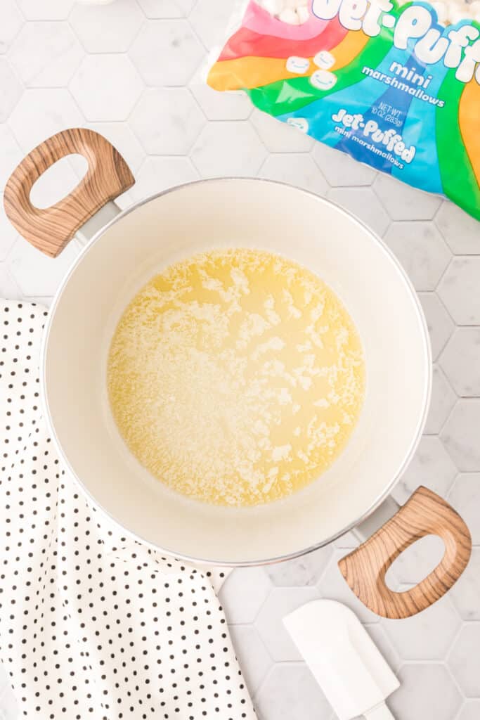 Melted butter in a saucepan during the first step of making cranberry orange crispy treats.