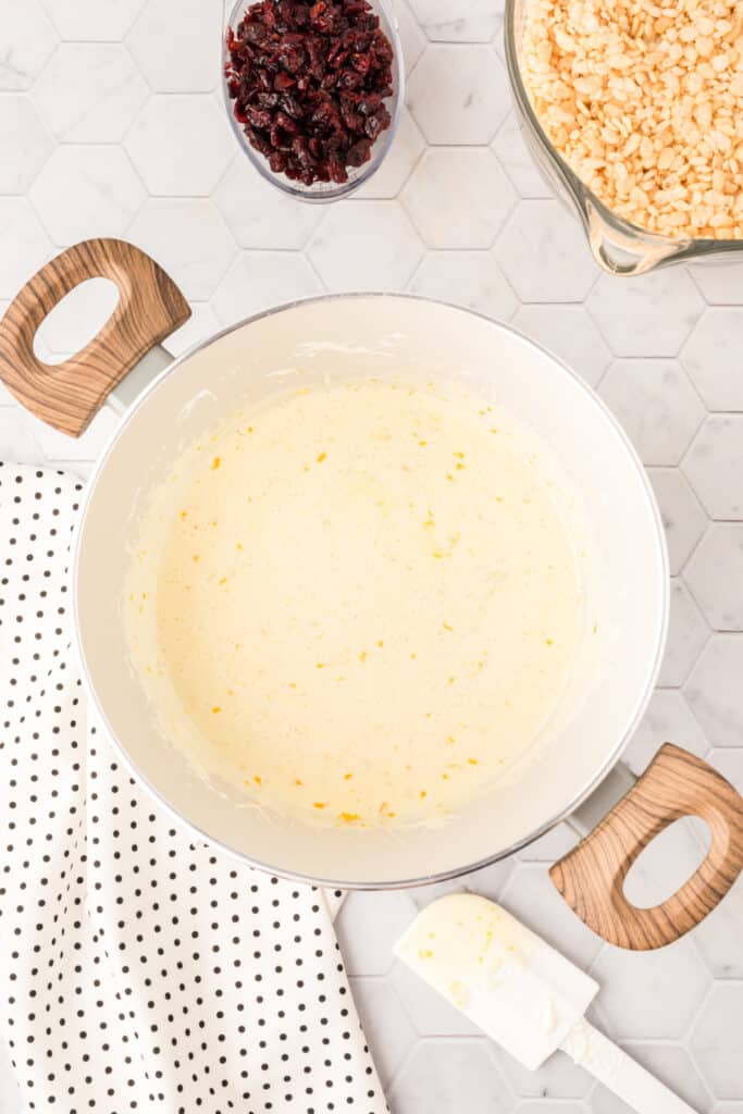 Orange-flavored marshmallow mixture ready for crisp rice cereal and dried cranberries.