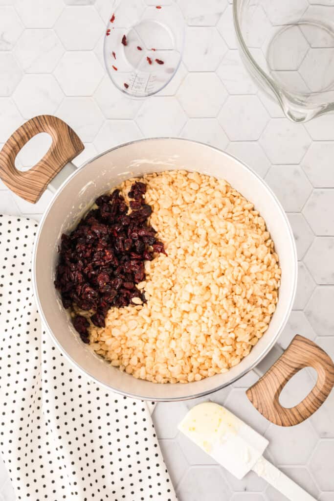 Crisp rice cereal and chopped dried cranberries added to the orange marshmallow mixture.