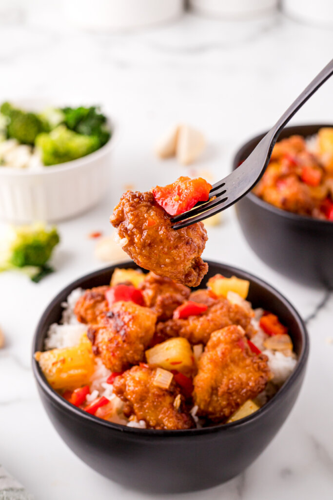 piece of sweet fire chicken being forked out of a bowl