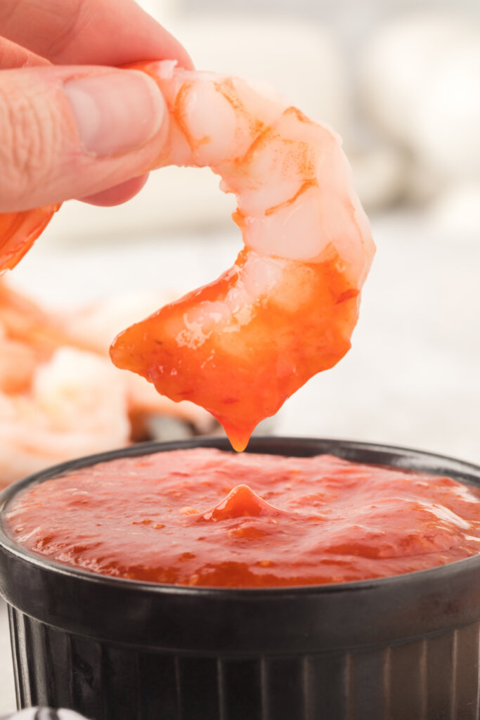 closeup of shrimp being dunked into shrimp cocktail sauce