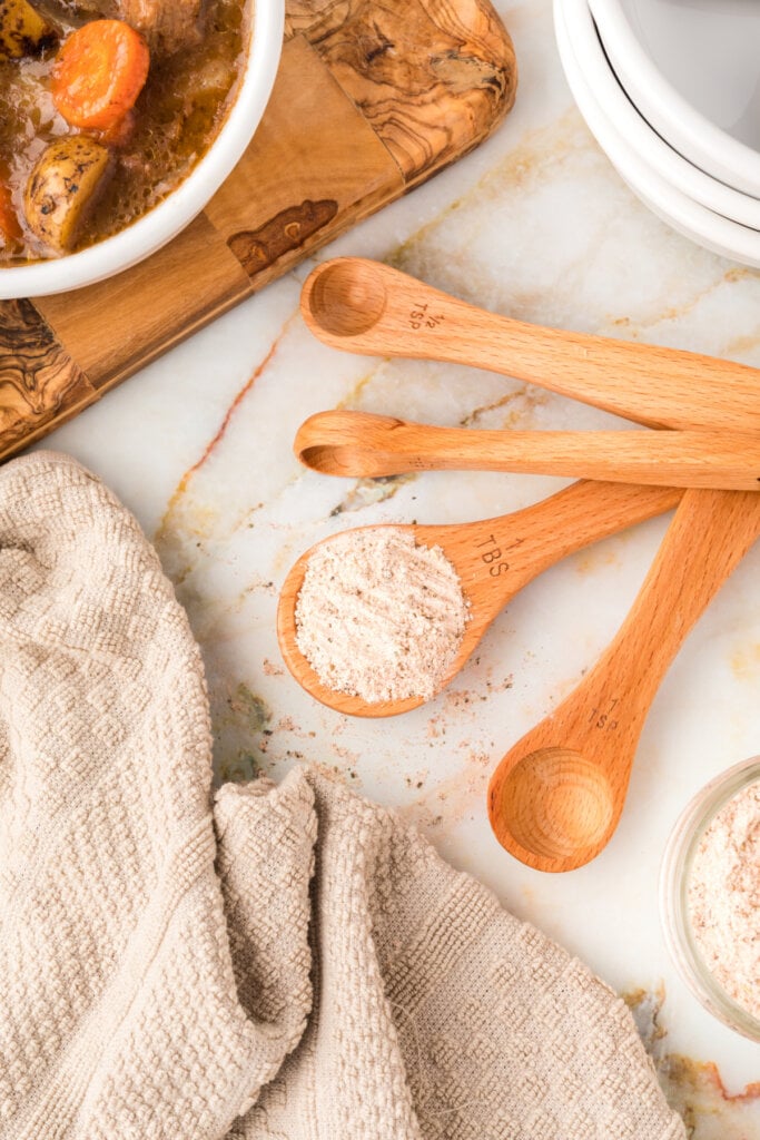 wooden measuring spoons with homemade beef stew seasoning mix in one of them