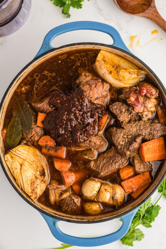 dutch oven with birria stew meat peppers and veggies