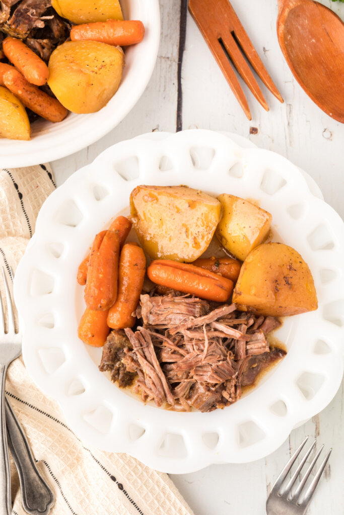 portion of roast beef with potatoes and carrots on white plate