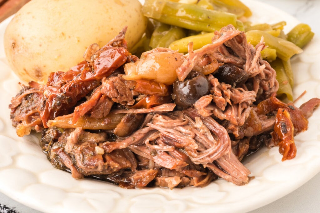 mediterranean pot roast on plate with potato and green beans