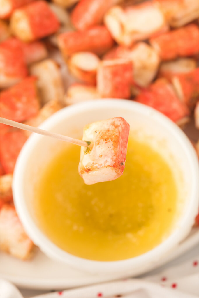 crab bite on toothpick getting ready to be dipped into garlic butter