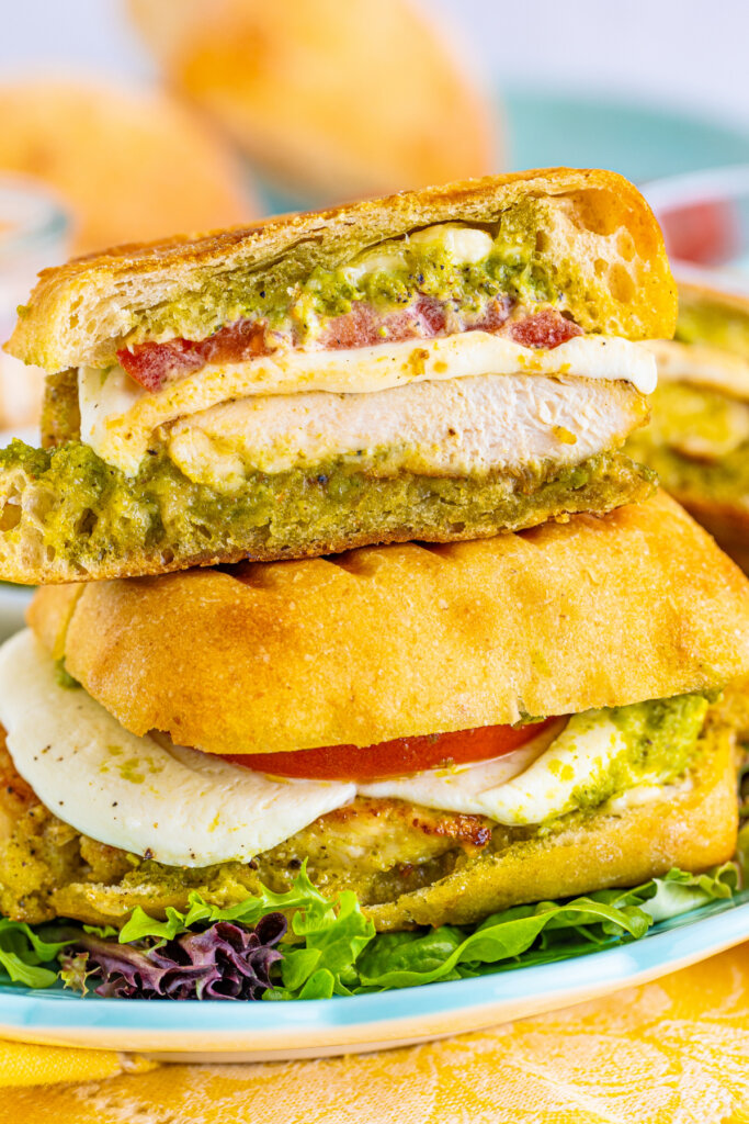 closeup of toasted pesto chicken sandwich cut in haf