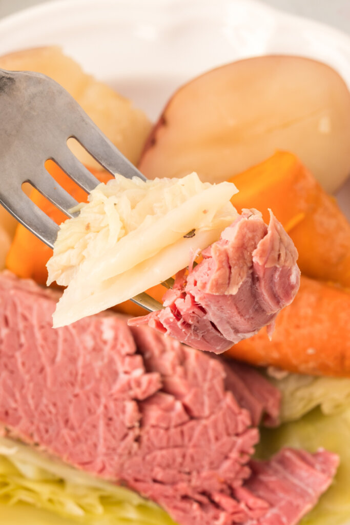 closeup of a bite of corned beef and cabbage on a fork