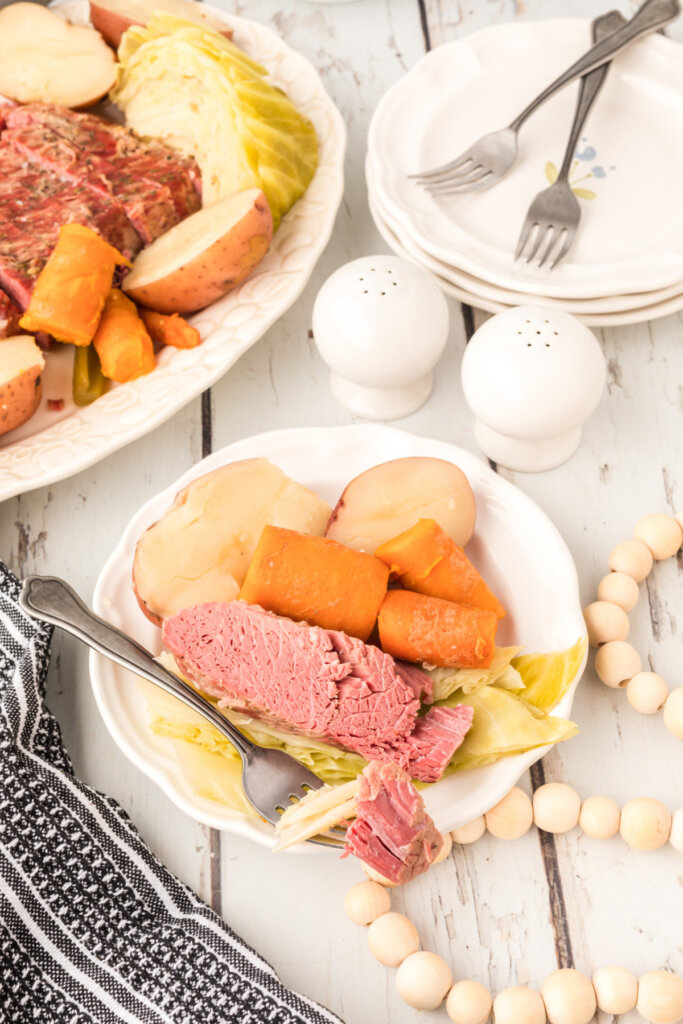 fork with a bite of corned beef and cabbage on plate