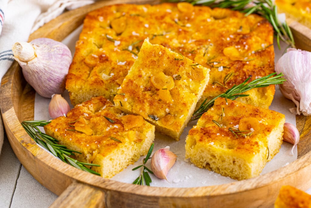 pieces of rosemary focaccia bread in wooden serving tray