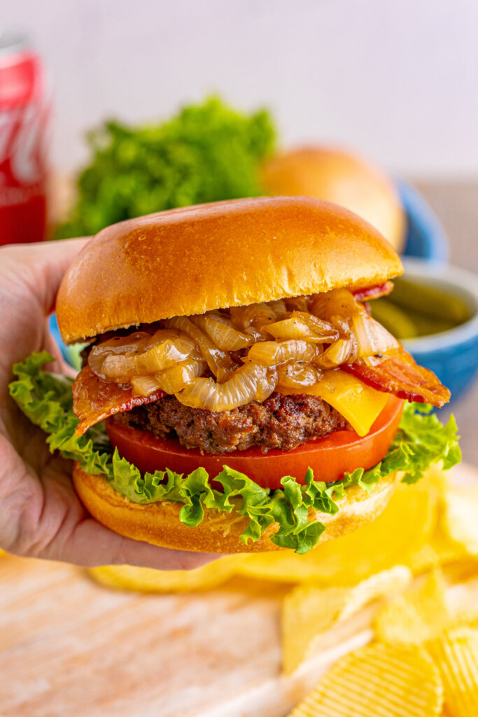 hand holding a bacon cheeseburger