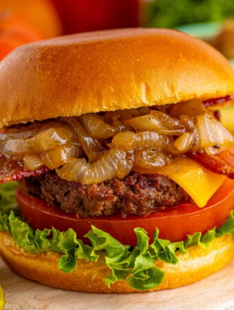 closeup of an assembled bacon cheeseburger with caramelized onions