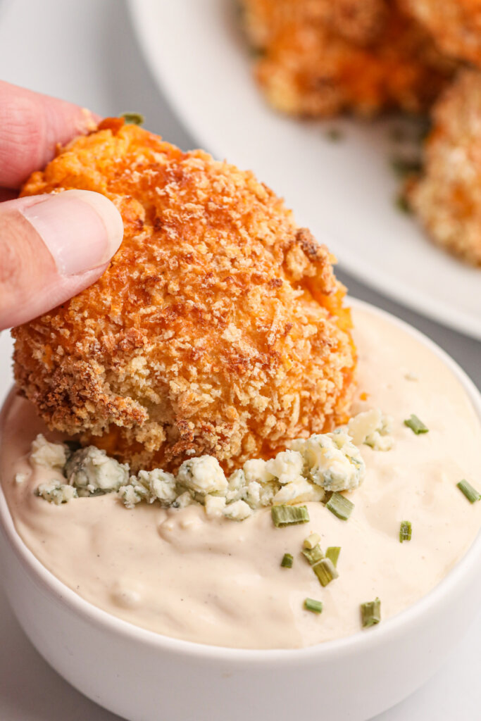 buffalo chicken popper being dipped into boue cheese dip