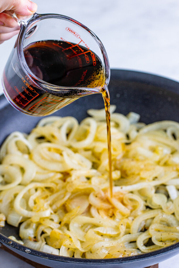 coca cola being poured into a skillet with onions