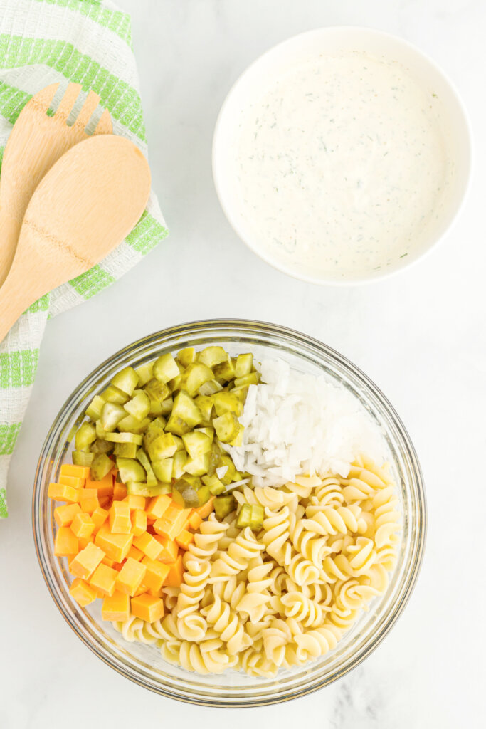 dill pickle pasta salad and dressing in bowls ready to be mixed