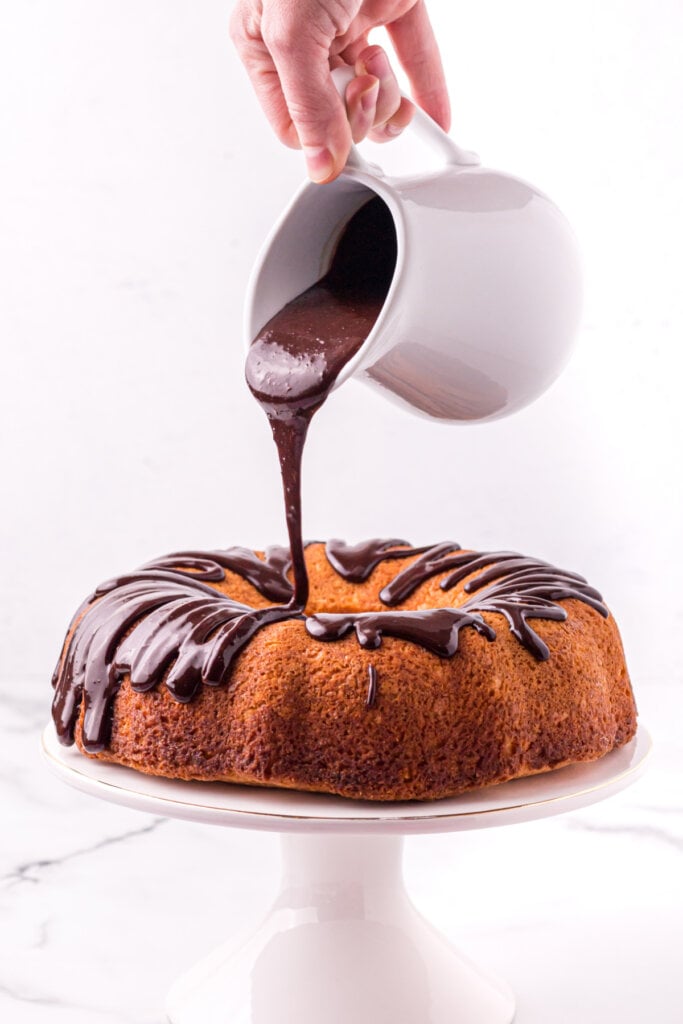 chocolate frosting being poured onto an ice cream bundt cake