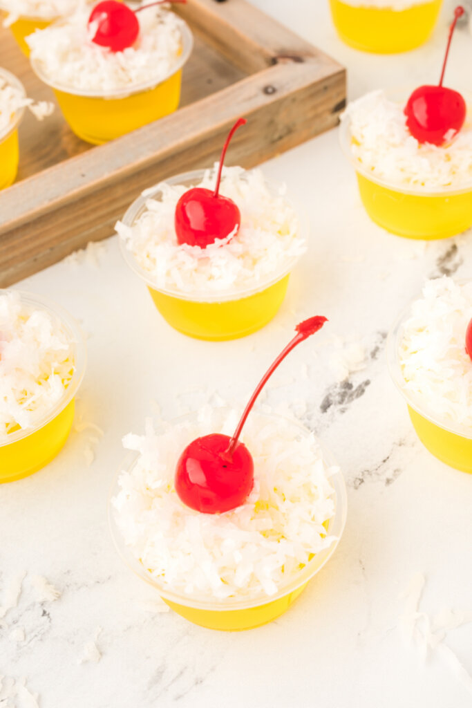 looking down onto a pina colada jello stot topped with shredded coconut and a maraschino cherry