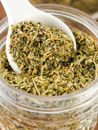 teaspoon scooping italian seasoning from glass jar