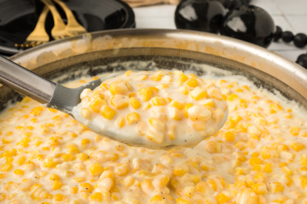 creamed corn on serving spoon over skilelt