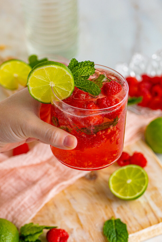 hand holding a berry vodka smash cocktail