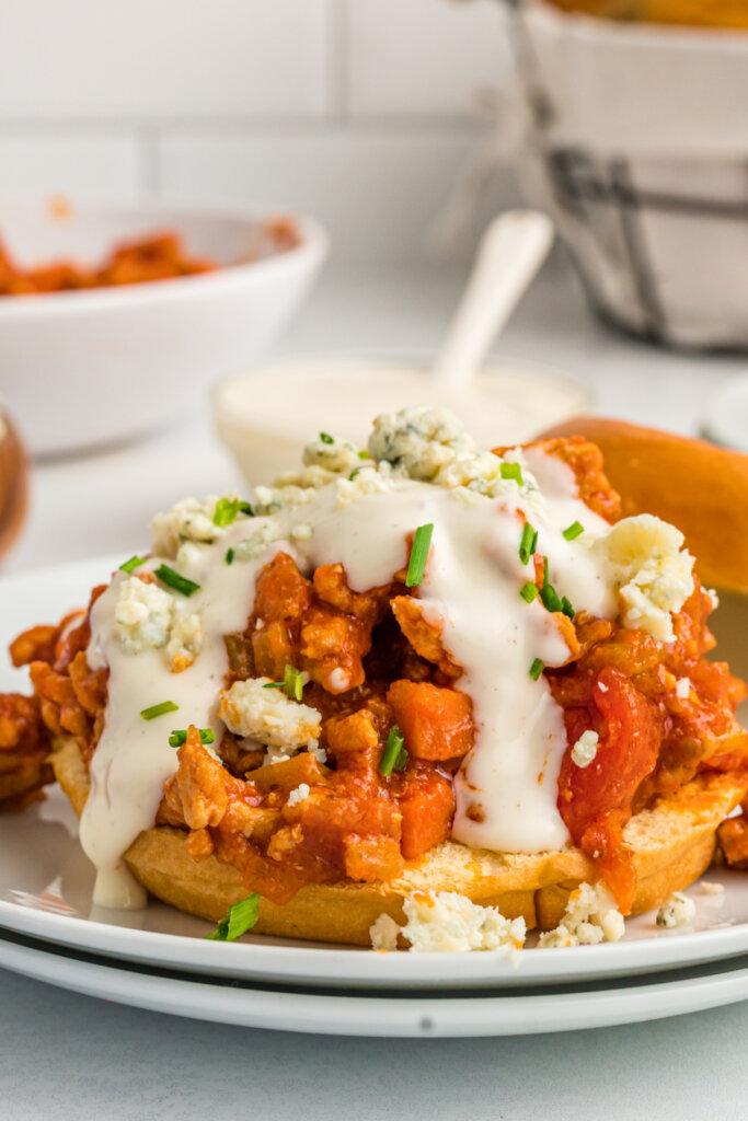 buffalo chicken sloppy joe without the top bun showing the ranch and blue cheese crumbles