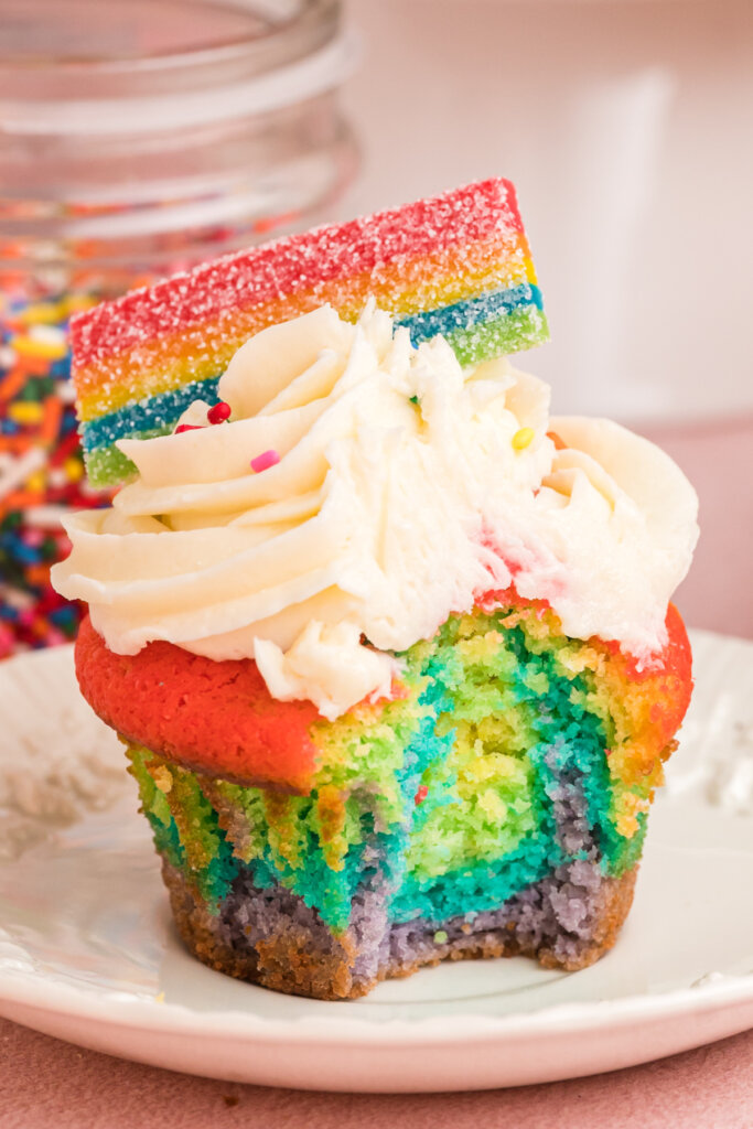 rainbow cupcakes with bite taken out to show the inside on plate