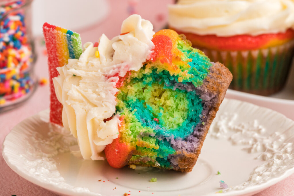 rainbow cupcake on its side with a bite taken out to show the inside
