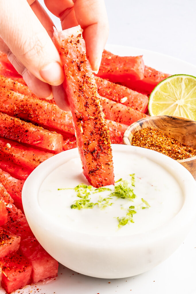 hand dipping spicy watermelon fries into coconut lime dipping sauce