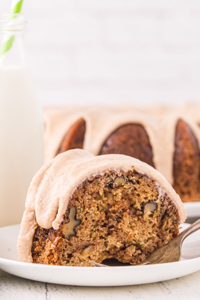 slice of zucchini bundt cake on plate in front of whole cake