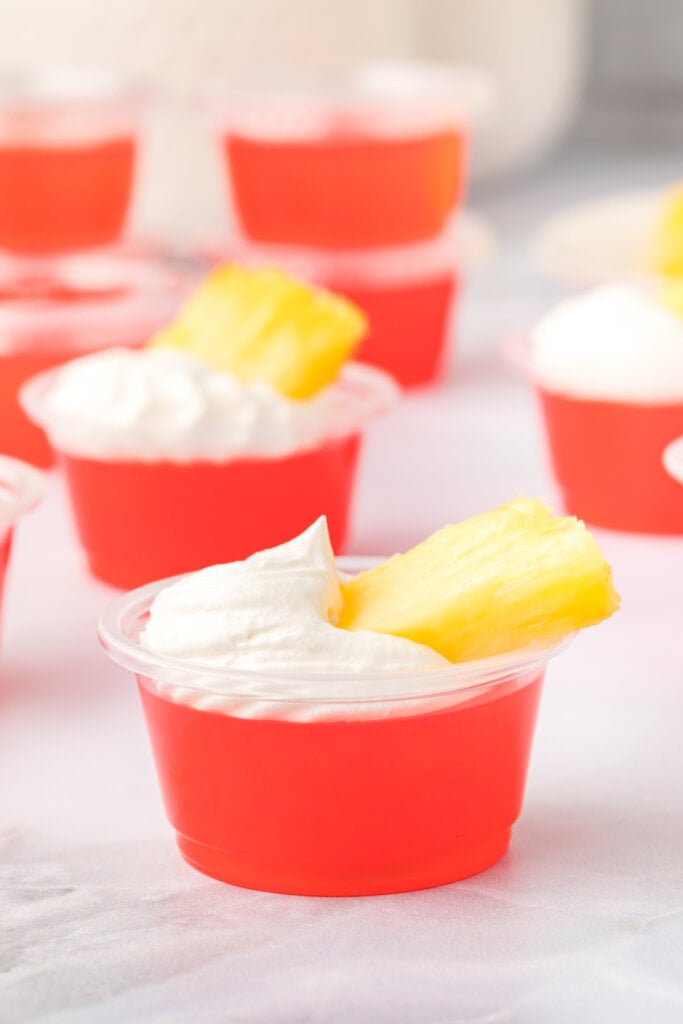 rum punch jello shots topped with whipped cream and a pineapple piece