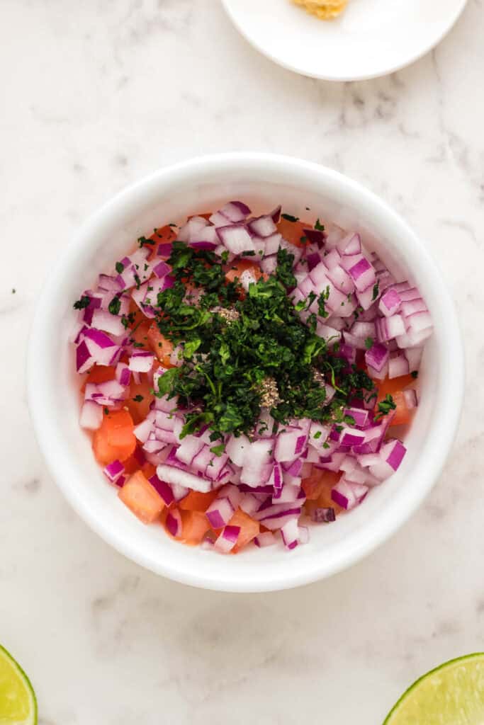 Fresh cilantro added to diced tomato and red onion for homemade salsa.