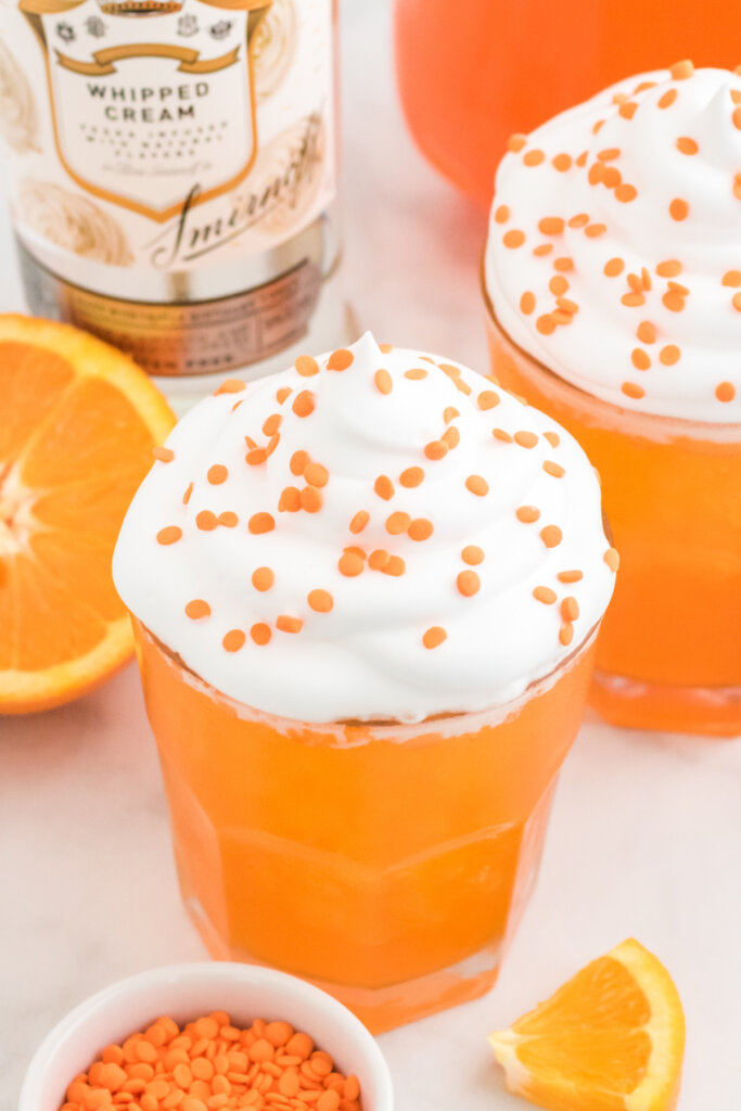 orange creamsicle cocktail garnished with whipped cream and orange sprinkles