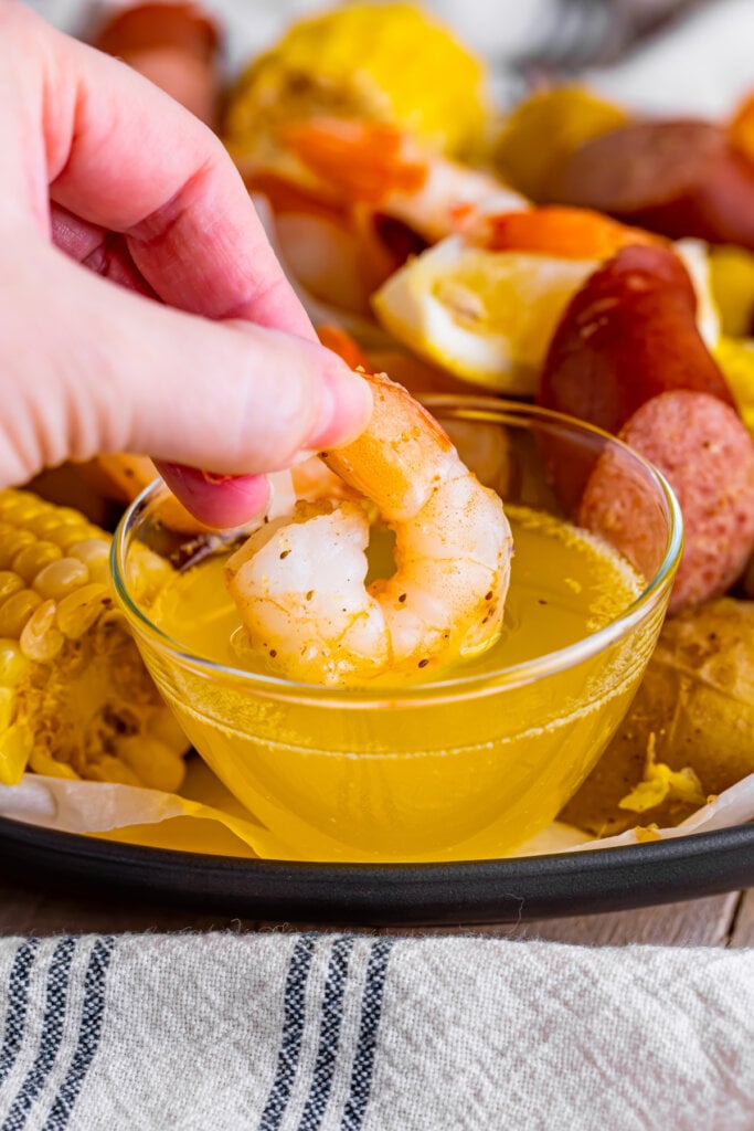 hand dipping shrimp in butter