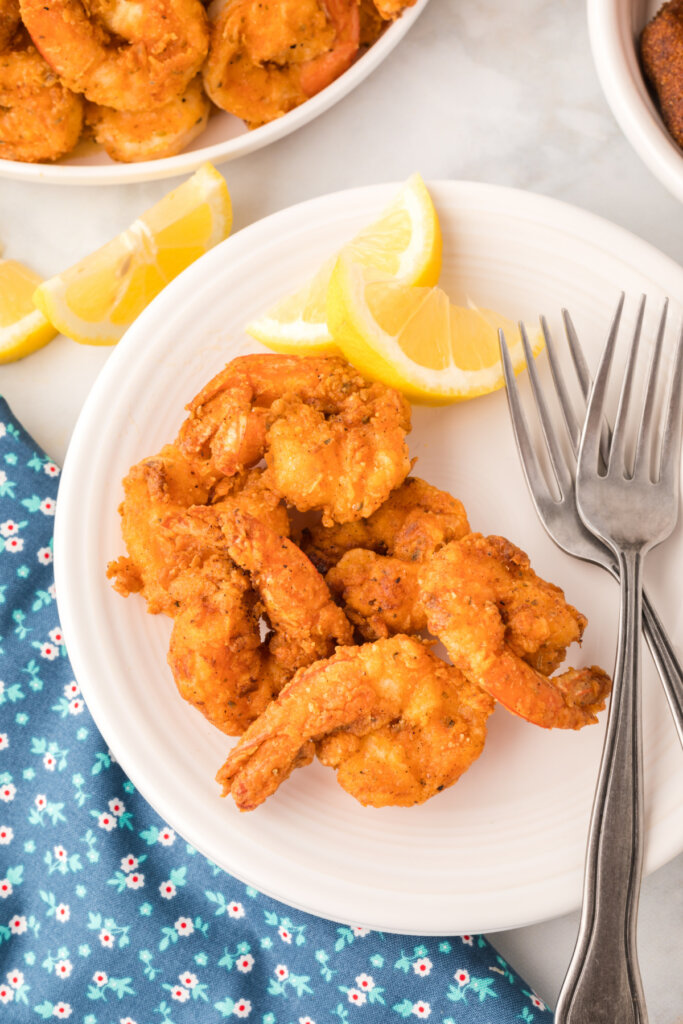 a serving of fried shrimp on plate with a lemon wedge
