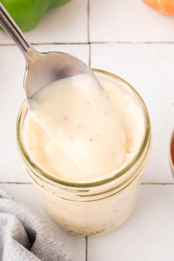 Spoonful of thick and creamy homemade condensed soup substitute lifted from a glass jar.
