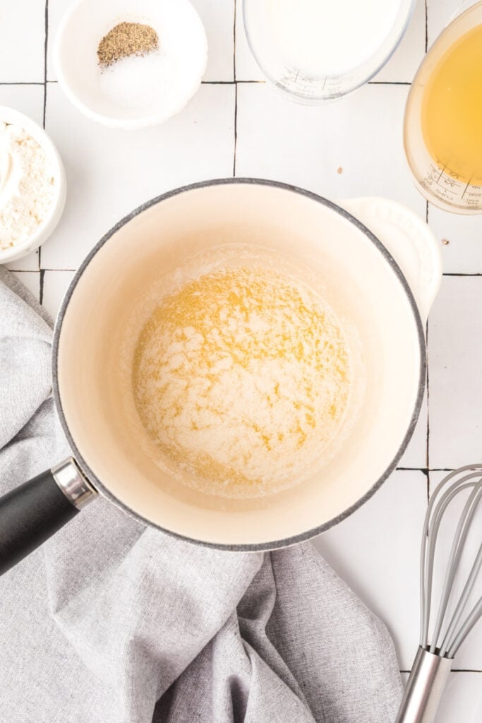 Melted butter in a saucepan with flour, milk, broth, salt, and pepper nearby.