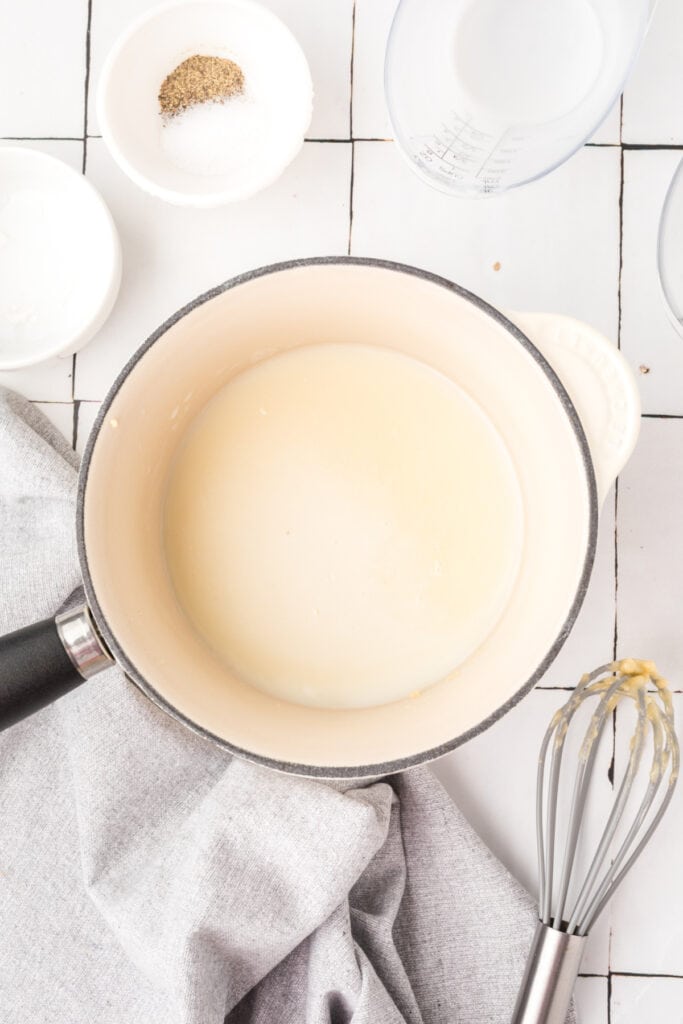 Milk added to the butter and flour mixture in a saucepan.