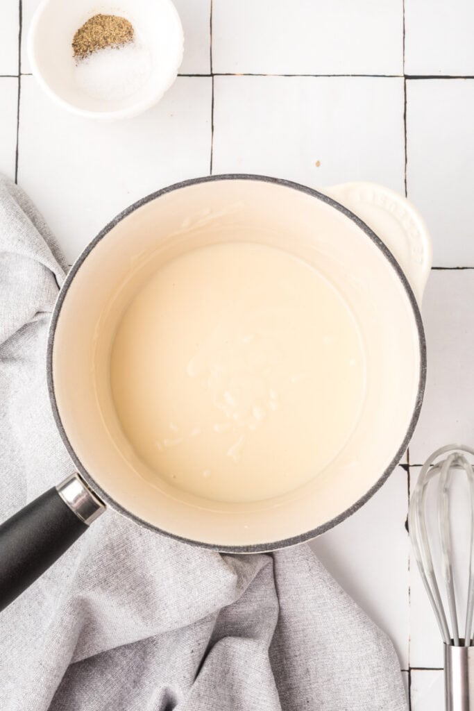 Cream soup mixture thickening in a saucepan after the liquid has been added.