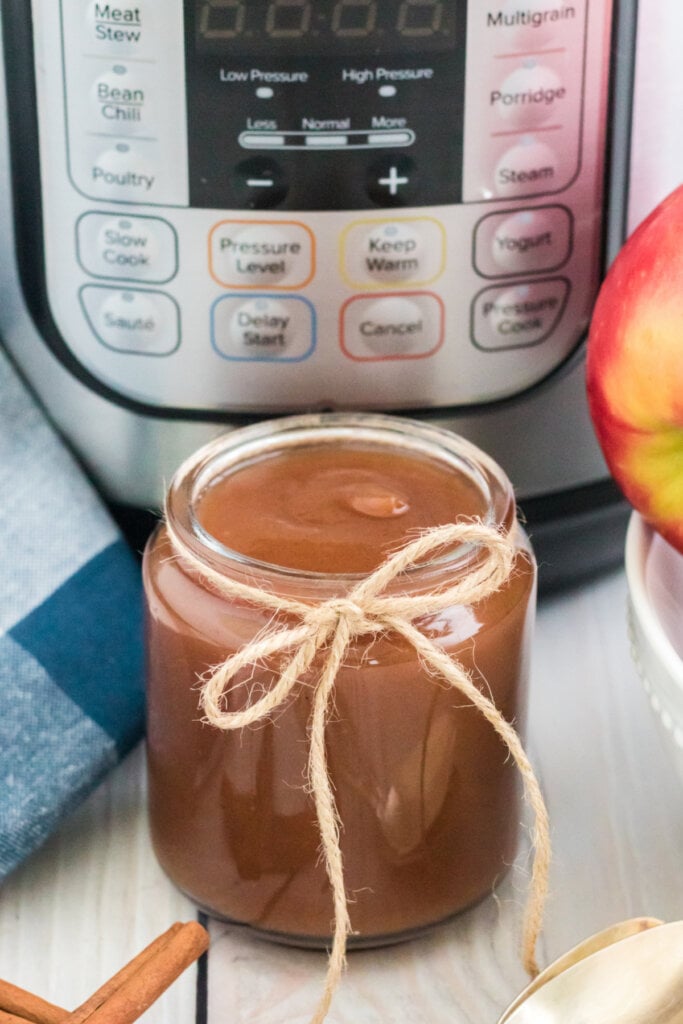 jar of homemade appl ebutter in front of an instant pot