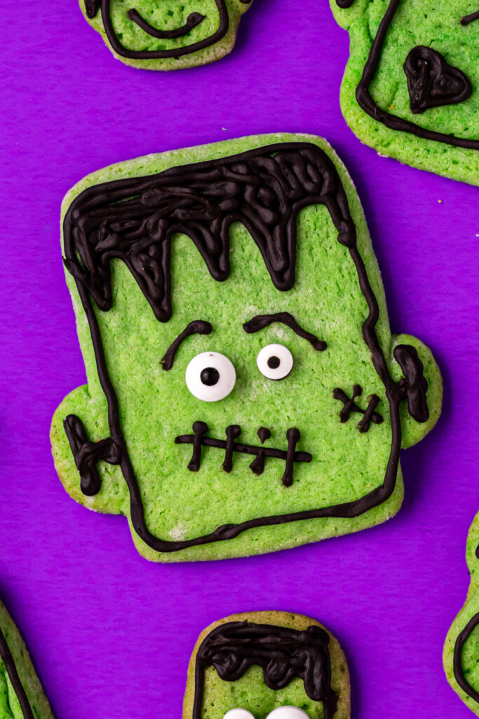 closeup of a decorated frankenstein cookie on a purple background